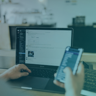 Image of someone typing on their computer while holding a phone