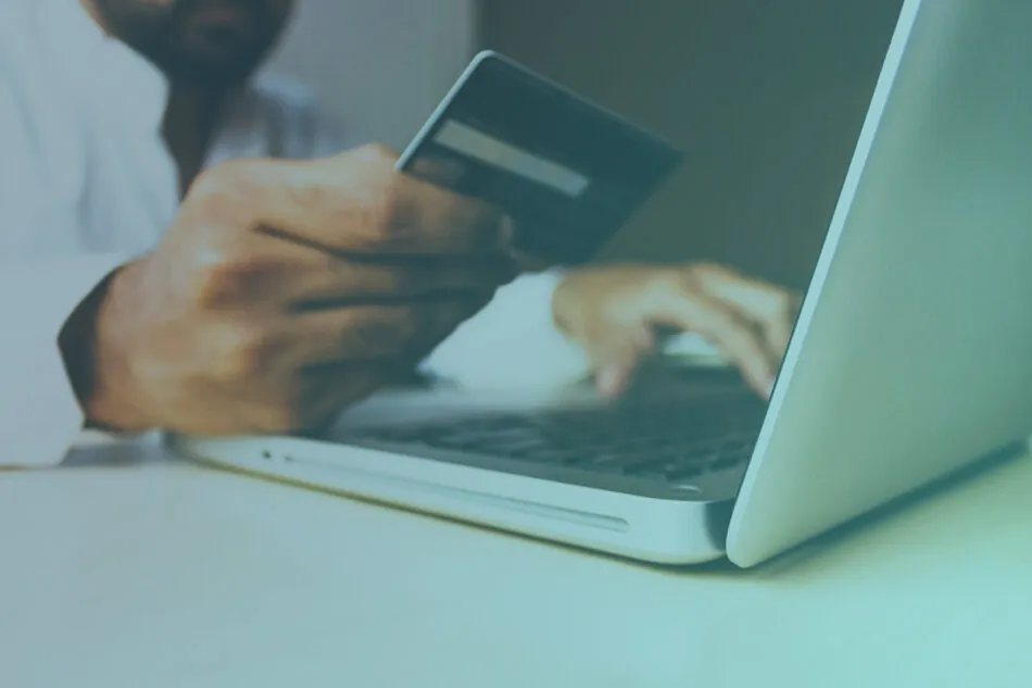 Image of someone typing on a laptop while holding a credit card