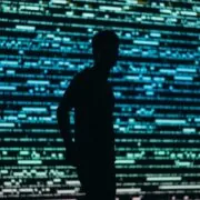 Silhouette of a man standing in front of a screen of colored lights